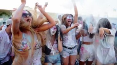 Zıplayan ve dans eden gençler Holi festivalinde yavaş çekimde havaya kuru boya atıp eğleniyorlar. Arkadaşlar Hindu tatilini kutluyor ve tecrit, covid salgın, karantina sona eriyor.
