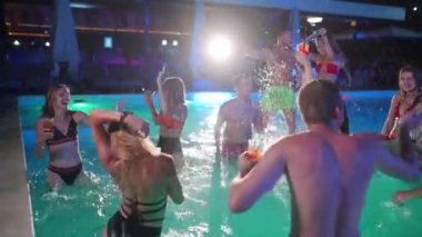 Arkadaşların özel bir yüzme havuzunda gece havuzu partisi var. Mayo giymiş neşeli genç insanlar su sıçratıyor, dans ediyor ve lüks otellerde parti yapıyorlar. Mutlu erkekler ve kadınlar birlikte takılıyor. Yavaş çekim.