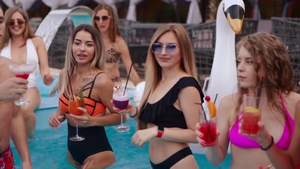 People have swimming pool party with cocktails at luxury resort. Friends in swimwear toasting and clinking glasses with drinks. Hot girls in bikini relax in the water. Slow motion — Stock Video