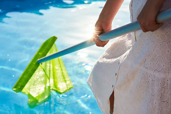 Mulher com equipamento de rede skimmer limpeza piscina de lixo. menina remove o lixo da água com uma seiva. Serviço de limpeza e manutenção de piscinas. Hotel limpador. — Fotografia de Stock