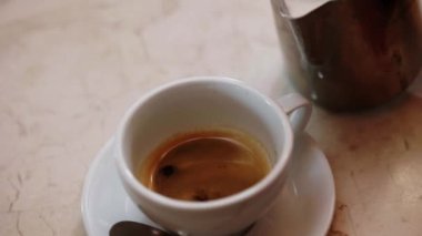 Beyaz bardakta cappuccino yapıyorum. Köpüklü süt espressoya döküldü. Kahve yapmanın aşamaları. Sıcak içecekler hazırlanıyor..