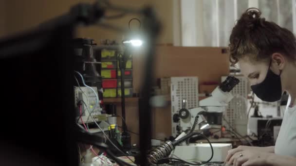 Arbeiterin in einem Service-Center mit Mikroskop und elektronischer Schalttafel. Mädchen schauen in der Werkstatt durch ein Mikroskop. Frauen und technische Berufe. — Stockvideo