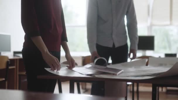 L'homme et la femme au bureau discutent du projet et apportent des changements. Ingénieurs hommes et femmes travaillant sur un projet, considérant les schémas, prenant des notes sur l'ordinateur portable. — Video