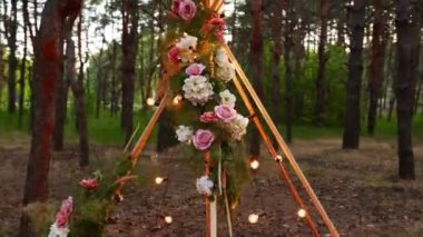 Pembe güllerle süslenmiş bohem tipi ahşap kemer, halıdaki mumlar, pampass çimenler, geceleri çam ormanlarındaki açık hava düğün mekânında peri ışıklarına sarılmış. Çiçeksel kompozisyonlar.