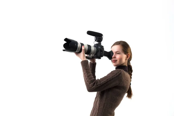 The beautiful photographer girl with professional dslr camera posing on a white background in studio. Photo learning, studying, training concept — Stock Photo, Image