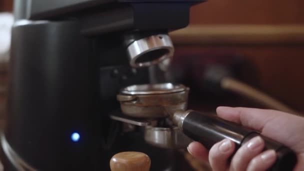 Kahve tutacağı, kahve dükkanındaki öğütülmüş kahveyle doldurmak için öğütücüye takılıyor. Barista tutucuyu eşit miktarda kahveyle doldurmak için çeviriyor. Kahve yapma sahnesi. — Stok video