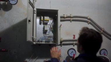 Elektrikçi sigorta kutusundaki şalterleri açar, ana güç teknik odadaki şalterleri açar. Eleman, bölgesel ısıtma istasyonunda elektrikli aletleri açıyor..