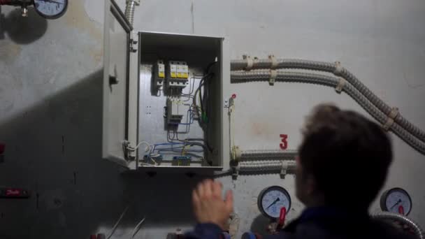 El electricista enciende los interruptores en una caja de fusibles, el maestro enciende los interruptores en la sala técnica. El hombre enciende aparatos eléctricos en una subestación de calefacción urbana. — Vídeo de stock