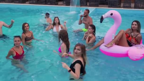 Friends have night pool party in a private villa swimming pool. Happy young people in swimwear splashing water, dancing with floaties and inflatable mattress in luxury resort. — Vídeo de Stock