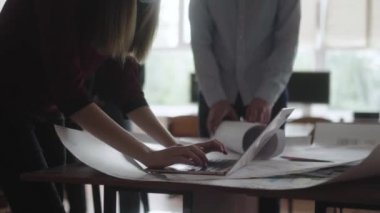 Ofisteki adam ve kadın projeyi tartışıp değişiklikler yapıyorlar. Erkek ve kadın mühendisler şemaları göz önüne alarak bir proje üzerinde çalışıyorlar, dizüstü bilgisayara not alıyorlar..