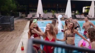 Bikinili gezgin blogcu kadın yüzme havuzunda arkadaşlarıyla fotoğraf çekiyor. Lüks otellerden seksi kızların olduğu bir video blogu. Kadın sosyal medyada canlı yayın.