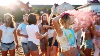 Pretty girl with tattoo smears hair with colored powder, shouts, turns head left and right, has fun at Holi festival. Woman shows freedom, end of covid restrictions and lockdown. Slow motion