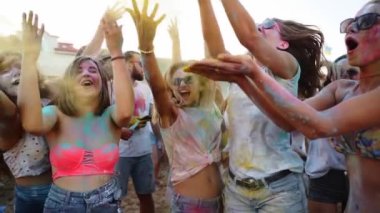 Renkli pudraya bulanmış kadınlara bağırmak Holi festivalini yavaş çekimde kutlamak için havaya kuru boya atmak. Açık hava Hindu tatil partisi. Kilitlemenin sonu, covid salgın, kısıtlamalar.