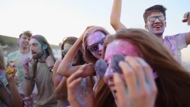 Cheerful people smeared in colorful powder laugh, shout, celebrate Holi festival in slow motion. Friends play with dry colors at hindu festival of spring, colours. End of covid pandemic isolation — Vídeo de Stock