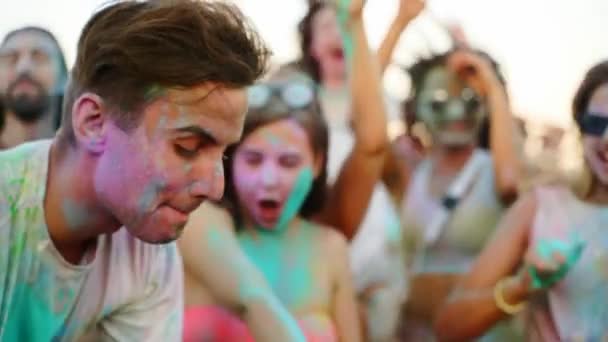 Veselí lidé slaví Holi festival potřísněný barevným práškem. Přátelé se bavte na hinduistické svátky jara, barev, lásky. Chlapi tancujou, skáčou zpomaleně na pláž. Konec kovidové pandemické izolace. — Stock video