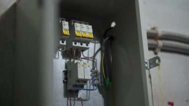 Elektrikçi sigorta kutusundaki şalterleri açar, ana güç teknik odadaki şalterleri açar. Eleman, bölgesel ısıtma istasyonunda elektrikli aletleri açıyor..