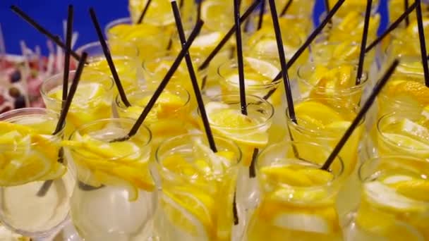 Okulary z lemoniadą w plasterkach owoców cytrusowych na stole w formie bufetu na cateringu. Letnia impreza detox na świeżym powietrzu. — Wideo stockowe