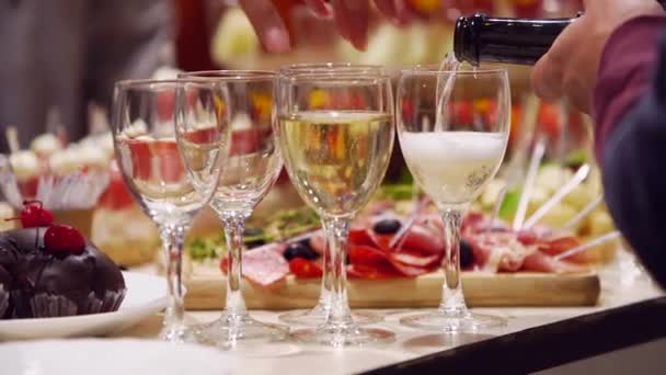 Waiter pouring glasses with champagne on catering service on banquet table with canape snacks in restaurant or hotel. Food set on birthday, wedding celebration or business conference event venue. — Vídeos de Stock