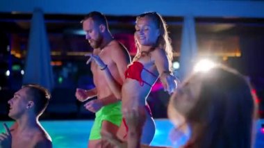 Arkadaşların özel bir yüzme havuzunda gece havuzu partisi var. Mayo giymiş neşeli genç insanlar su sıçratıyor, dans ediyor ve lüks otellerde parti yapıyorlar. Mutlu erkekler ve kadınlar birlikte takılıyor. Yavaş çekim.
