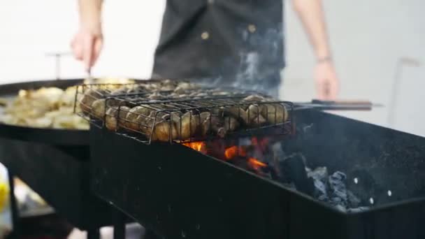 Gros plan du chef qui fait frire des champignons sur des brochettes sur une grande cuisinière industrielle grill à l'extérieur pour un service de restauration. Le cuisinier tourne crache sur le barbecue. — Video