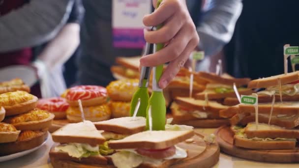 Servicio de catering en una mesa de banquetes con hamburguesas, bocadillos, rosquillas y sándwiches en restaurante u hotel. Conjunto de alimentos decorados en el cumpleaños, celebración de la boda o lugar del evento de la conferencia de negocios. — Vídeos de Stock