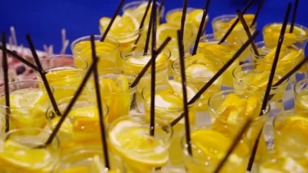 Sklenice s limonádou s plátky citrusových plodů na jídelním stole formou bufetu. Letní detox party venku. — Stock video