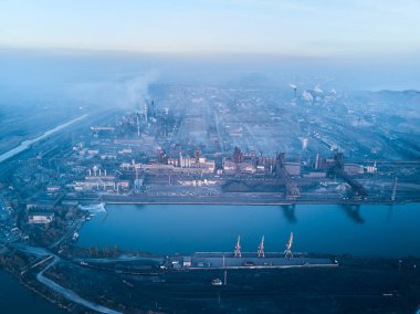 Metalurjik santralden kaynaklanan hava ve su kirliliği ve deniz limanı yakınlarındaki fırınlarla dolu bir sanayi şehri. Kirli duman, çelik fabrikasının borularından çıkan duman. Ekolojik konular kavramı.