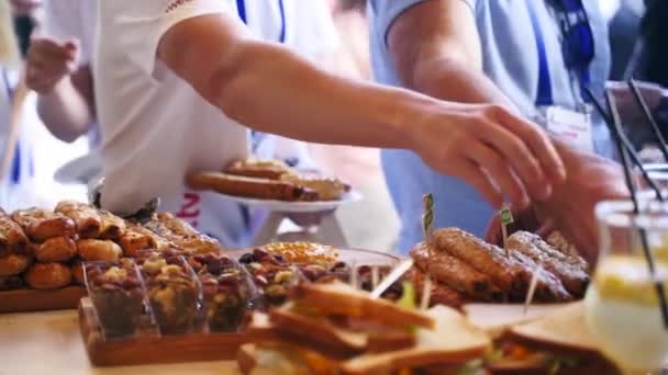 Catering service on a banquet table with burgers, puffs, donuts and sandwiches in restaurant or hotel. Decorated food set on birthday, wedding celebration or business conference event venue. — Wideo stockowe