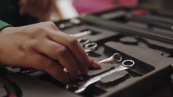 Master puts a wrench into a tool box and takes pliers from it. Woman mechanic takes instruments for car repair job. — Video Stock