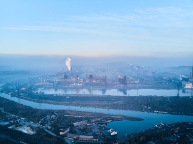 Metalurjik santralden kaynaklanan hava ve su kirliliği ve deniz limanı yakınlarındaki fırınlarla dolu bir sanayi şehri. Kirli duman, çelik fabrikasının borularından çıkan duman. Ekolojik konular kavramı.