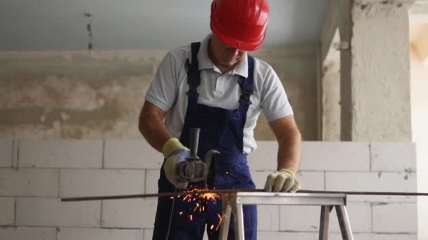 Trabajadores de la construcción profesionales manos en guantes de trabajo utilizando amoladora angular para cortar varilla de metal en el sitio de construcción. Primer plano de contratista cortando palo de hierro con chispas brillantes en cámara lenta. — Vídeo de stock