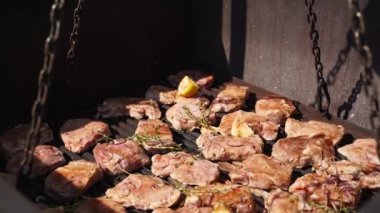 Yemek servisi için açık havada büyük bir endüstriyel fırında et kızartıyoruz. Aşçı kızarmış domuza baharat ve bitkiler döktü..