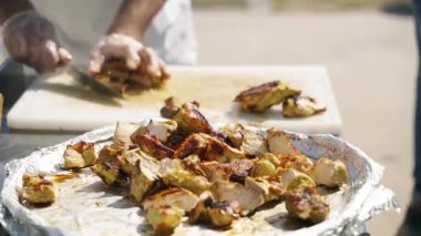 Şef bıçakla sıcak et bifteği keser ve et parçalarını tabağa koyar..