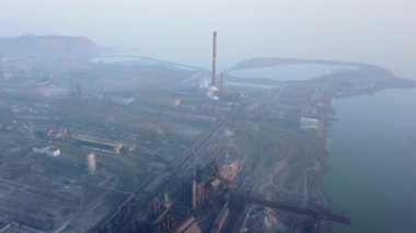 Aerial of industrial city with air atmosphere and river water pollution from metallurgical plant and blast furnaces near sea. Dirty smoke, smog from pipes of steel factory. Ecological issues concept.