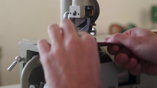 Artisanat en cuir travaille en atelier. Maître fabrication de produits en cuir. Homme travaillant avec une machine d'amincissement de skiving de cuir électrique ou une pelle coupante plate industrielle, mesures avec jauge d'épaisseur. — Video