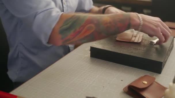 L'artisan du cuir travaille dans son atelier. Maître faisant portefeuille en cuir. Homme coupe des trous avec piquer des outils de poinçonnage en cuir poinçon piquant et marteau. — Video