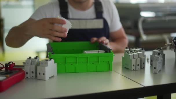 전기 기술자는 전기 패널 퓨즈 상자를 작업장에 조립 한다. 노동자 테이블에 배포보드에 에너지 측정기, 스위치 및 회로 차단기를 설치. — 비디오