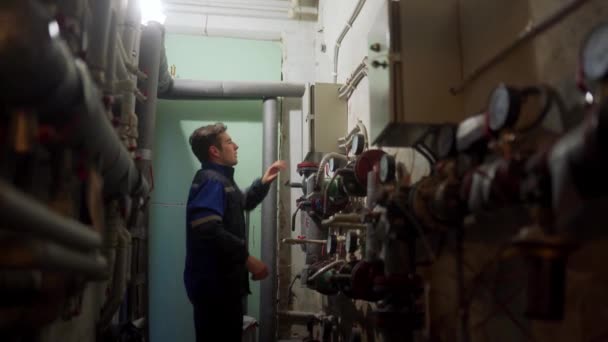 Elektriker demontiert Sicherungskasten. Meister in Uniform schrauben elektrische Platte, um Elektrizität zu beheben. Mann kontrolliert Schalttafel im Technikraum einer Fernwärme-Umspannstation. — Stockvideo