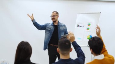 İş adamı antrenörü sunar konferans salonundaki çizelgelerde şemaları gösterir. Seyirciler bir ofiste sunum için el kaldırır. Usta sınıftan izleyiciye öğretmen.