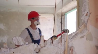Adam elle sökme ve yıkım işleriyle uğraşıyor. Dairenin tadilatı için büyük çekiçle vuruyor. Müteahhit balyozla duvarı yıkar ve yeniden düzenleme için delik açar. Üniformalı inşaat işçisi.