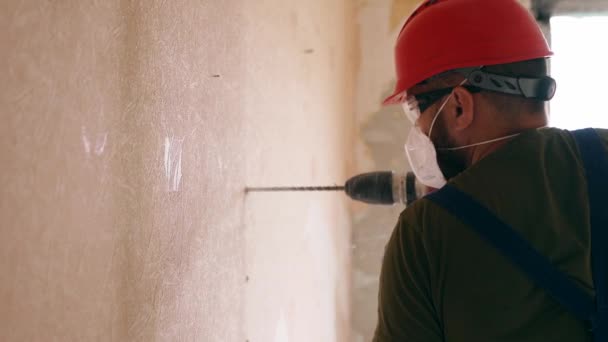 ロータリーハンマードリルで作業ビルダー 請負業者は アパートの改装や改装のための壁を取り壊すためにジャックハンマーでコンクリートで穴を開けます 均一な設置配線の電気技師 — ストック動画