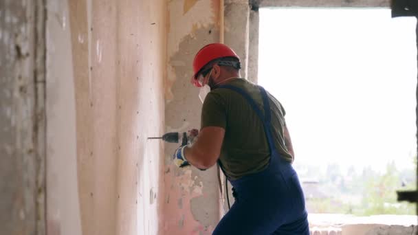 建筑工人用旋转锤头钻头工作 承包商用钻钻钻在混凝土上打孔 以拆除墙壁 进行公寓改造和翻新 身穿制服的电工安装电线 — 图库视频影像