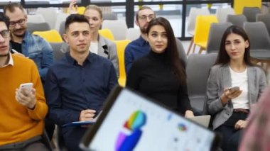 Dinleyiciler iş toplantısı ya da konferans hakkında tablet ve diyagramlarla sunucuya bakıyor. İnsanlar brifingde kadın konuşmacıya sorular soruyorlar. Proje sunum yöneticisi raporundaki çalışanlar.