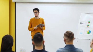 İş adamı antrenörü bir rapor sunar, konferans salonundaki çizelgelerde şemaları gösterir. Proje yöneticisi ofiste sunumla ilgili soruları tartışıyor. Usta sınıftan izleyiciye öğretmen.