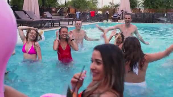 朋友们在一个私人别墅游泳池里举行夜池派对 快乐的年轻人穿着水花四溅的泳衣 在奢华的度假胜地与鲜花和充气床垫共舞 — 图库视频影像
