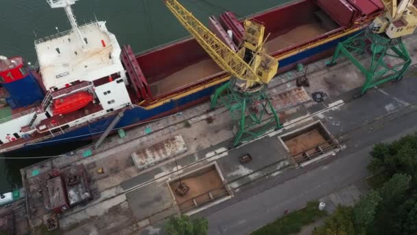 コンテナから貨物船への穀物輸送は 海上港のガントリークレーン上のデュアルスクープクラムシェルグラブを保持しています 水輸送付きダンプトラックからの小麦の出荷 商品輸送 — ストック動画