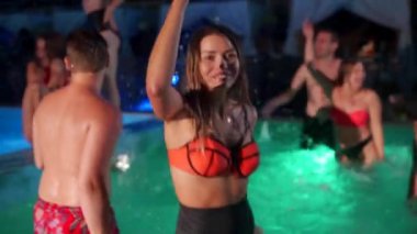 Bikinili güzel bir kadın kokteyl içiyor ve gece havuzu partisinde arkadaşlarıyla takılıyor. İnsanlar lüks bir özel yüzme havuzunda içkilerle dans edip su sıçratarak eğleniyorlar. Yavaş