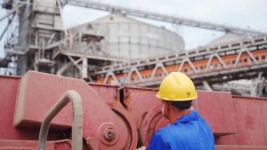Denizci, limandaki deniz tahıl terminalinde buğday gemisindeki kargo ambarlarını güvenli bir şekilde kilitlemek için koruyucu kurşun mührü takıyor. Nakliye acentesi nakliye için konteynır kapısını kilitliyor.