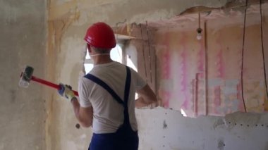 Müteahhit balyozla duvarı yıkar ve yeniden düzenleme için delik açar. İnşaat işçisi elle söküyor, yıkıyor ağır çekiç darbeleriyle dairenin yenilenmesini sağlıyor..