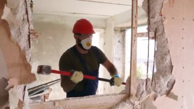 Adam elle sökme ve yıkım işleriyle uğraşıyor. Dairenin tadilatı için büyük çekiçle vuruyor. Müteahhit balyozla duvarı yıkar ve yeniden düzenleme için delik açar. Üniformalı inşaat işçisi.